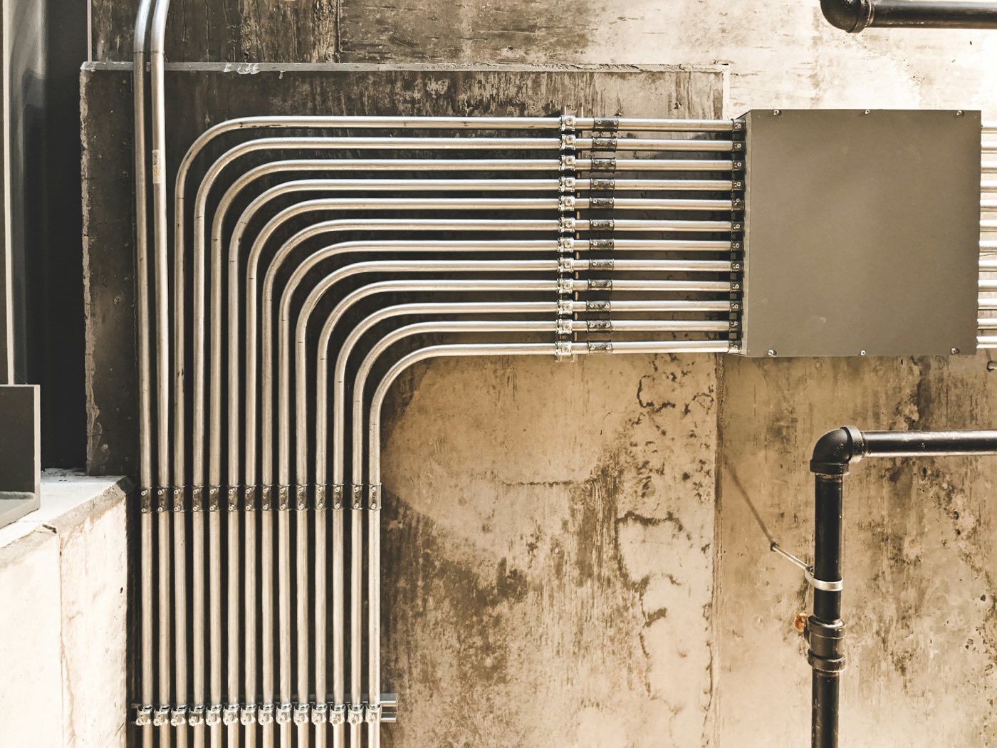 Bent stainless steel pipe runs along a wall